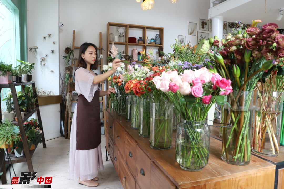 王黎媛是一名河南姑娘，在昆明念完大學(xué)后，就再也舍不下春城的藍(lán)天陽光、青山碧水，更舍不下這里的四時繁花，于是就干脆留了下來，成了一名媒體人。2017年的時候又毅然辭去工作，創(chuàng)業(yè)開起了花店，成了都市里的一名“花房姑娘”。圖為王黎媛在自己的花店中整理鮮花。新華網(wǎng) 周亞平/攝 念新洪/文